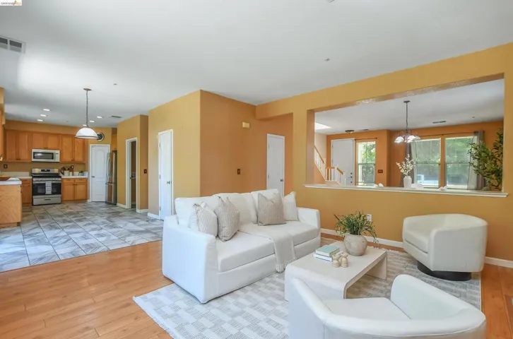 Open-concept living space featuring wood-finish flooring, a kitchen with stainless steel appliances, and an architectural pass-through window