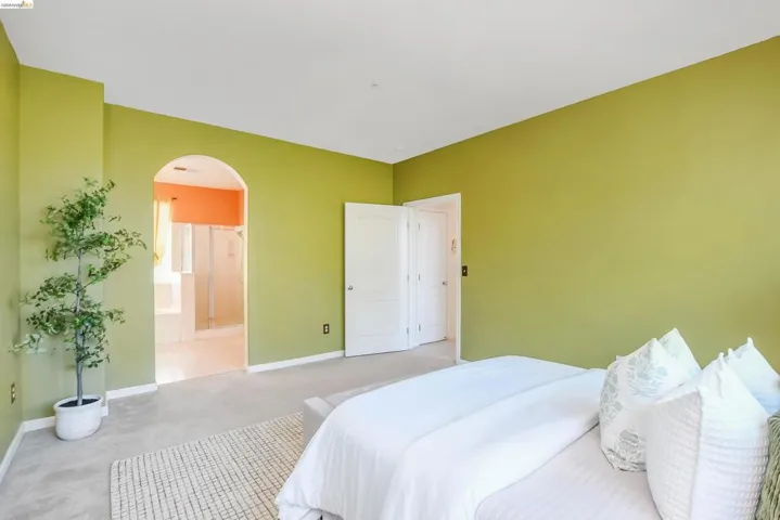 Spacious bedroom featuring light green walls and light-colored carpeting