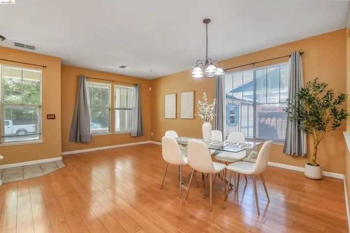 Open-concept living area featuring wood-finish flooring, multiple large windows, and a ceiling-mounted light fixture