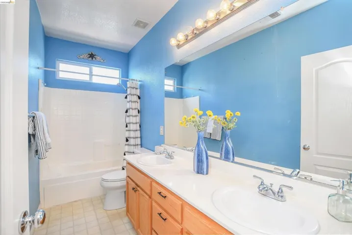 Bathroom featuring a dual vanity with light wood cabinetry, a white countertop, and two undermount sinks