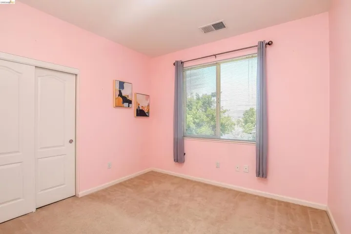 Room featuring neutral carpet flooring, a dual-pane window with horizontal blinds, and a sliding two-panel closet door