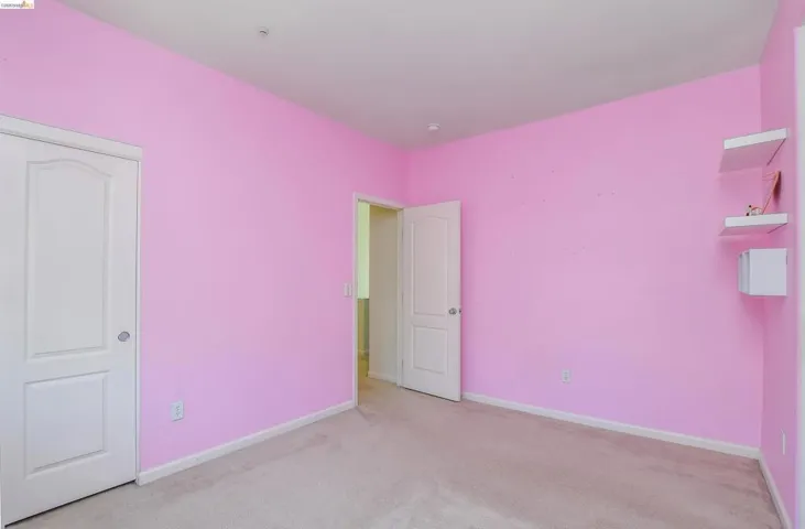 Carpeted interior space featuring white trim, two panel doors, and built-in wall shelving