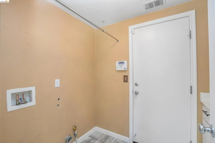 Dedicated utility space featuring a white door, light tan walls, and a tiled floor
