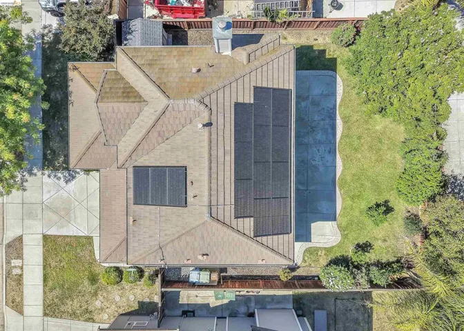 Residential property with a multi-pitched roofline, solar panel arrays, and a curved swimming pool