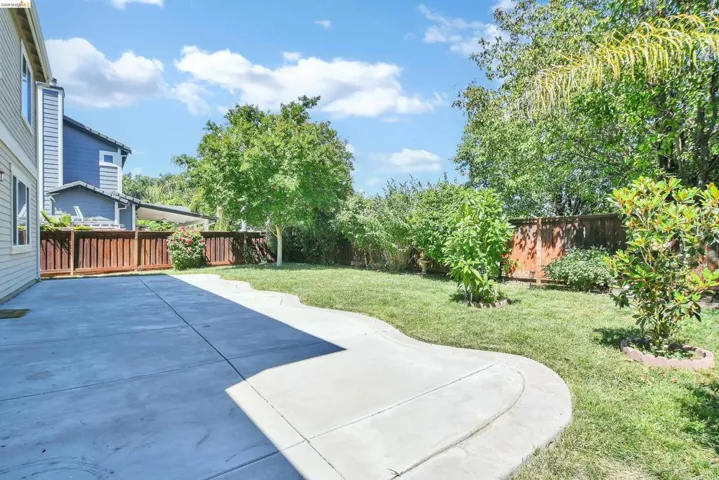 Expansive concrete patio with a curved walkway leading to a lush lawn