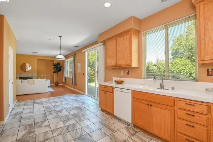Kitchen featuring wood cabinetry, white tile countertops, and an undermount sink with a gooseneck faucet