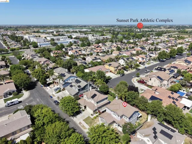 Residential neighborhood with established homes, mature trees, and visible solar panel installations on multiple rooftops