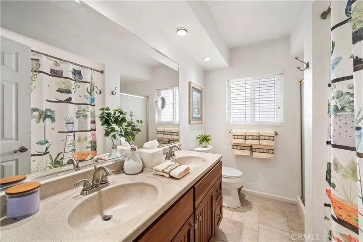 Upstairs bathroom is upgraded with Silestone-type countertop, dual sinks, travertine-style tile flooring, a soaking tub, and a separate shower