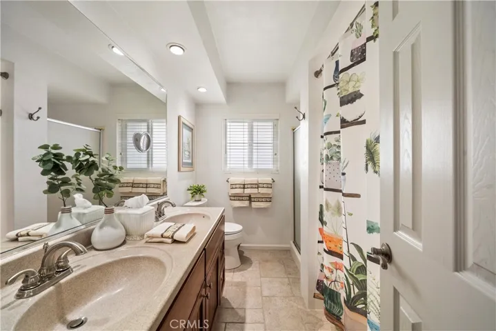 Upstairs bathroom is upgraded with Silestone-type countertop, dual sinks, travertine-style tile flooring, a soaking tub, and a separate shower