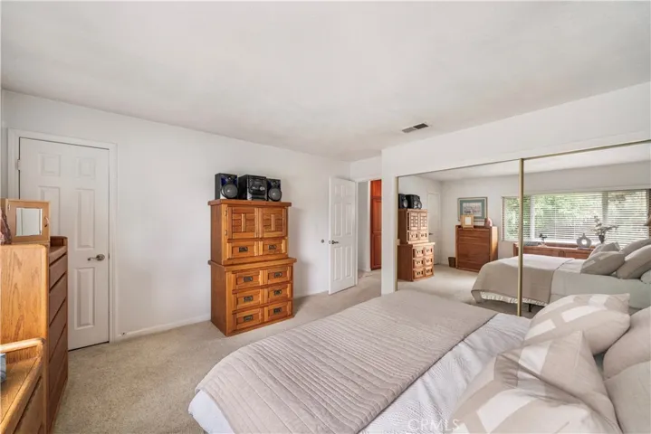 Primary bedroom with custom organizers in the mirrored closet