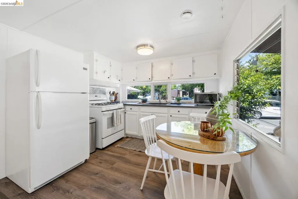 Bright kitchen featuring white cabinetry, a gas range, wood-finish flooring, and ample natural light from multiple windows