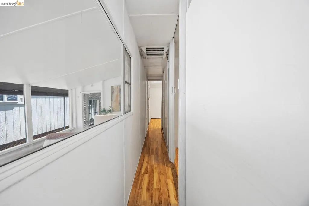 Elongated hallway featuring wood-finish flooring, white walls, and a recessed ceiling