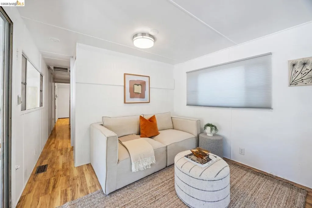 Bright interior space featuring wood-finish flooring, white walls, and a contemporary flush-mount ceiling light
