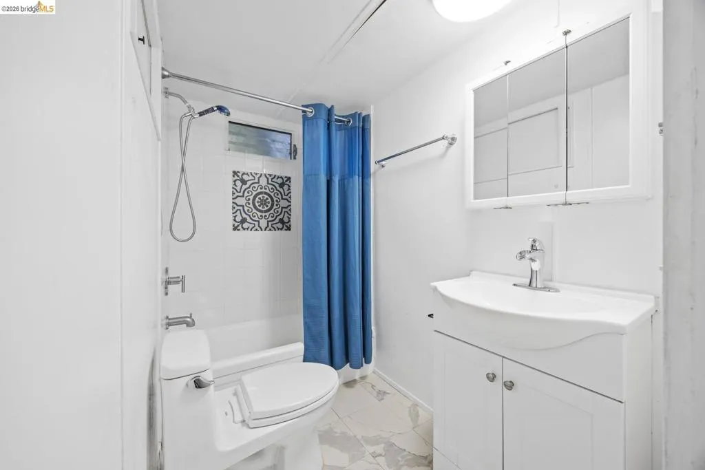 Bathroom featuring a white vanity with integrated sink, mirrored medicine cabinet, and white subway tile shower surround with decorative accent tiles