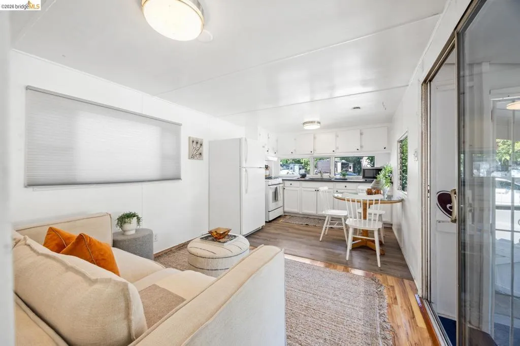 Open-concept living space featuring wood-finish flooring, white cabinetry, and a sliding glass door