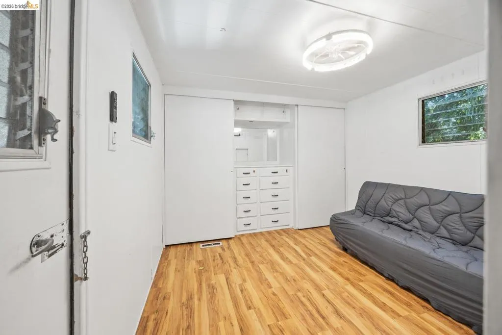 Room featuring wood-finish flooring, white walls, and a built-in storage unit with​​‌​​​​‌​​‌‌​​‌​​​‌‌​​​‌​​‌‌​​‌‌​​‌‌​​​​ drawers