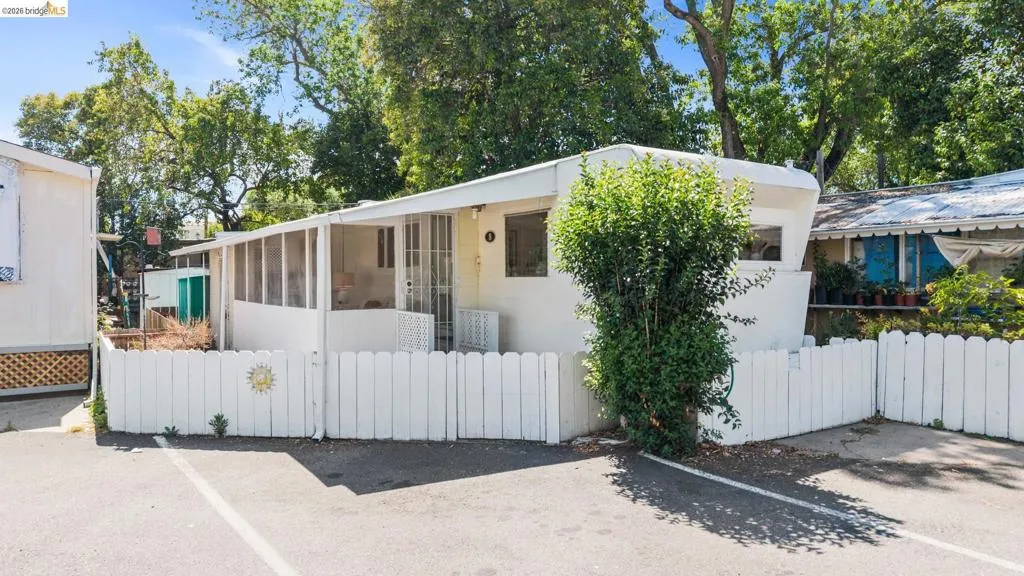 Mobile home featuring white exterior siding, a screened-in porch, and a white picket fence