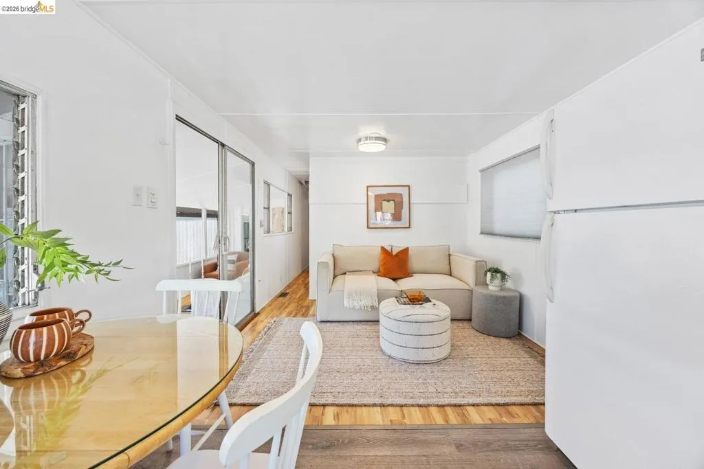 Open-concept living area featuring wood-finish flooring, white walls, and a recessed ceiling light fixture