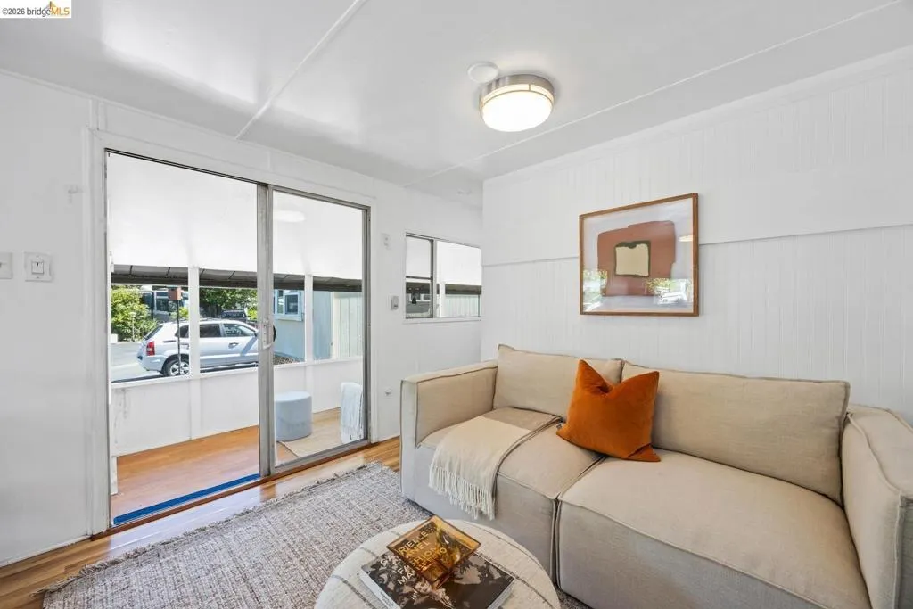 Bright living area featuring white paneled walls and wood-finish flooring