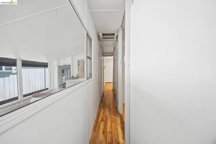 Elongated hallway featuring wood-finish flooring, white walls, and a recessed ceiling