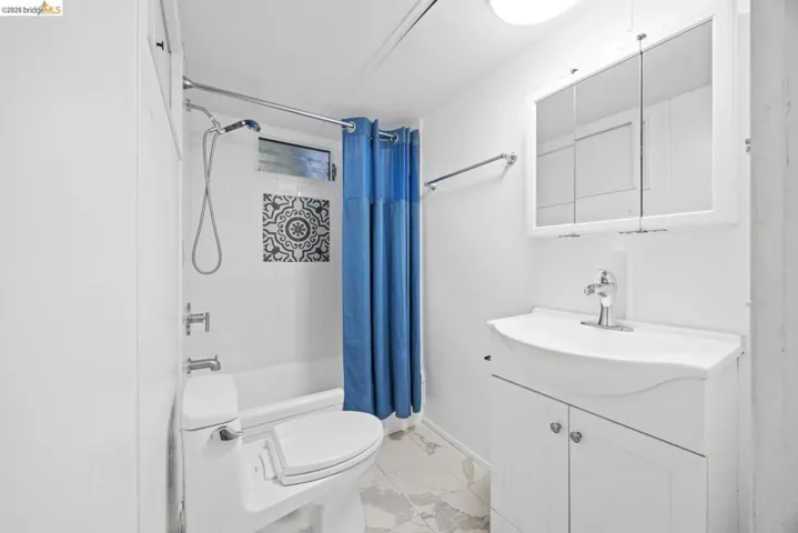 Bathroom featuring a white vanity with integrated sink, mirrored medicine cabinet, and white subway tile shower surround with decorative accent tiles