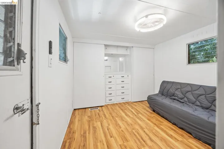 Room featuring wood-finish flooring, white walls, and a built-in storage unit with​​‌​​​​‌​​‌‌​​‌​​​‌‌​​​‌​​‌‌​​‌‌​​‌‌​​​​ drawers