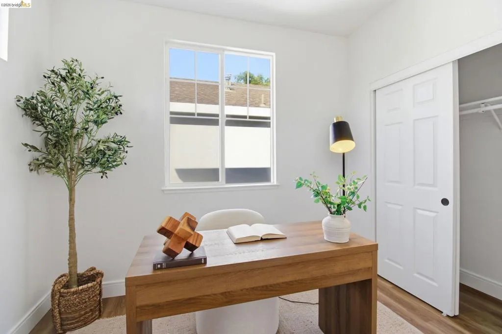 Room featuring a large window, white walls, and wood-finish flooring