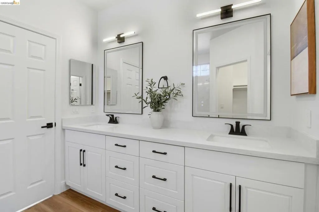 Bathroom featuring a dual vanity with white shaker cabinetry, matte black hardware, quartz countertops, and undermount sinks