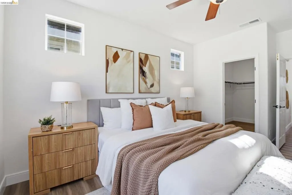 Bedroom featuring wood-finish flooring, a ceiling fan with integrated lighting, and high windows for natural light