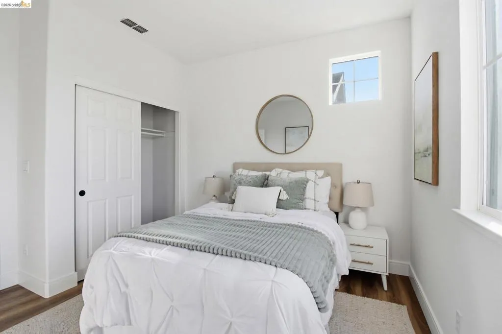 White-painted room featuring wood-finish flooring, a two-panel sliding closet door, and two windows