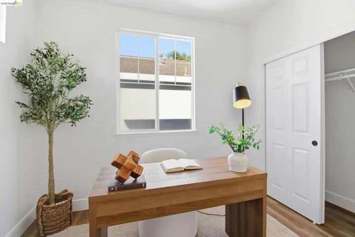 Room featuring a large window, white walls, and wood-finish flooring