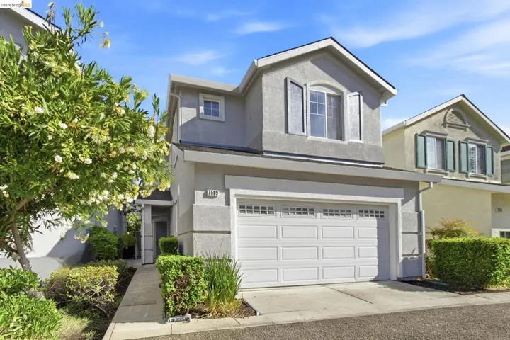 Stucco exterior featuring an attached garage and a concrete pathway