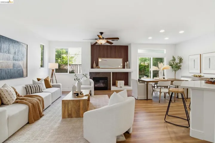 Open-concept living space featuring wood-finish flooring, a fireplace with a wood-paneled accent wall, and recessed lighting
