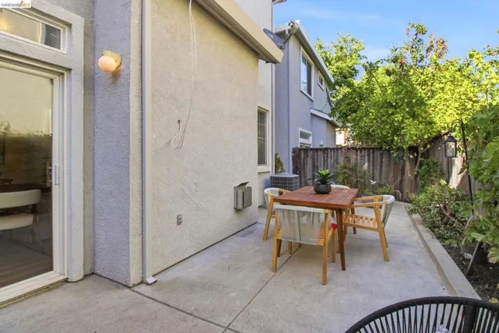 Concrete patio area featuring a sliding glass door and perimeter landscaping