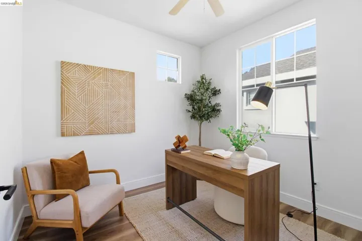 Bright room featuring high ceilings, wood-finish flooring, a contemporary ceiling fan, and large windows