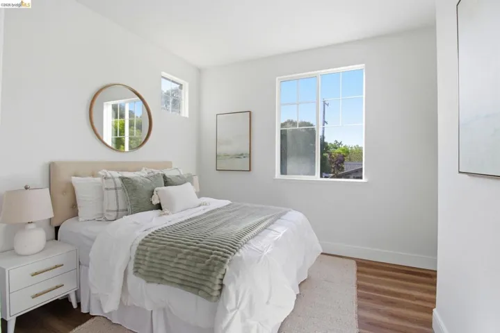 Bedroom featuring wood-finish flooring, white walls, and a large window with grid panes