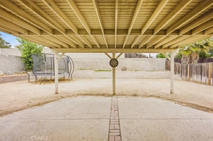 Large covered patio area with brick detailing. Lots of flat yard area along with some planters around the side and back