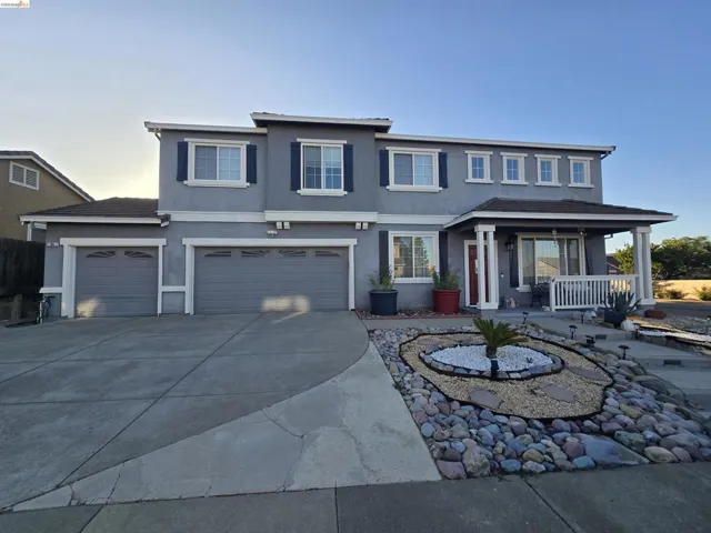 Two-story stucco residence featuring a covered front porch with white railings and columns