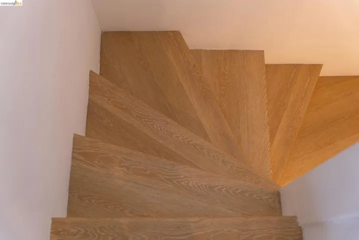 Wood-finish spiral staircase with white wall paneling