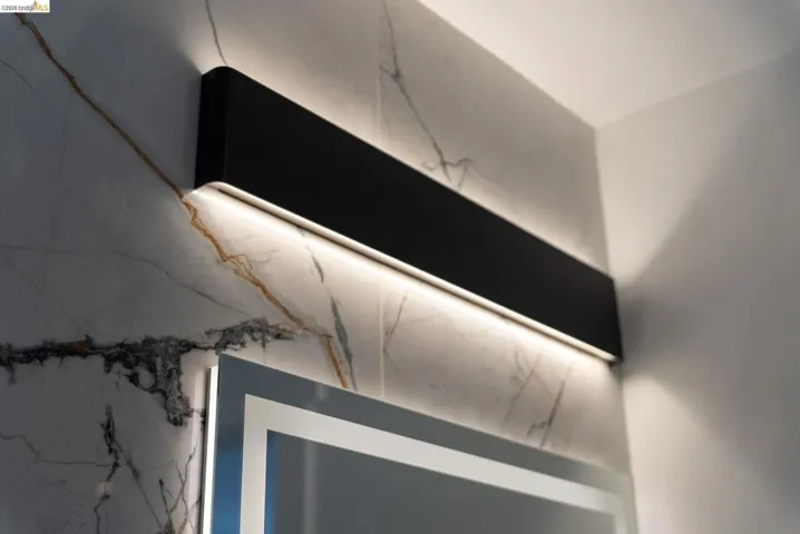 Modern wall-mounted light fixture featuring a matte black finish and integrated LED illumination, set against a marble-look wall with distinctive veining