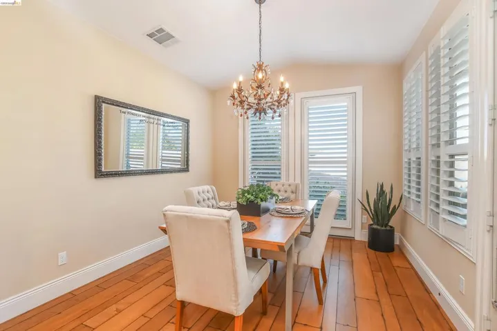 Warm-toned wood-finish flooring complements the neutral wall color in this dining area