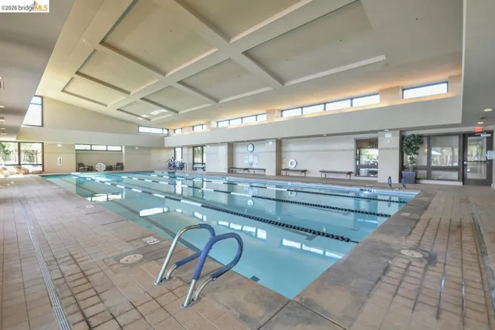 Indoor lap pool featuring a coffered ceiling, clerestory windows, and perimeter windows