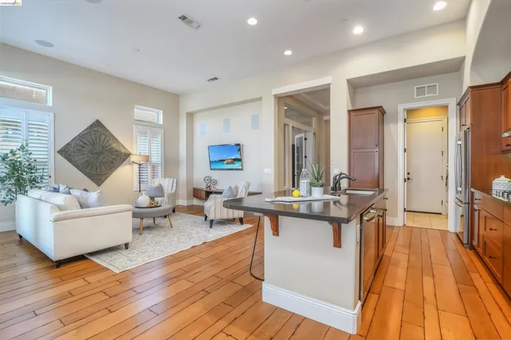 Open-concept living space featuring wood-finish flooring, plantation shutters, and recessed lighting