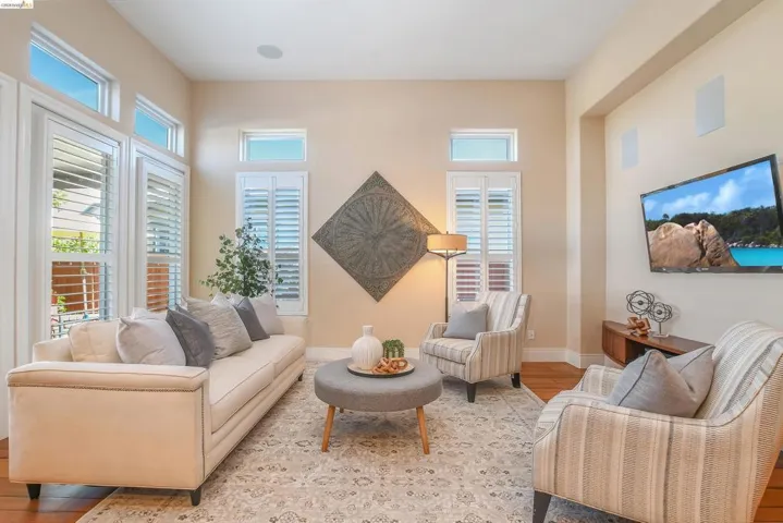 Living area featuring wood-finish flooring, light-toned walls, and a large area rug