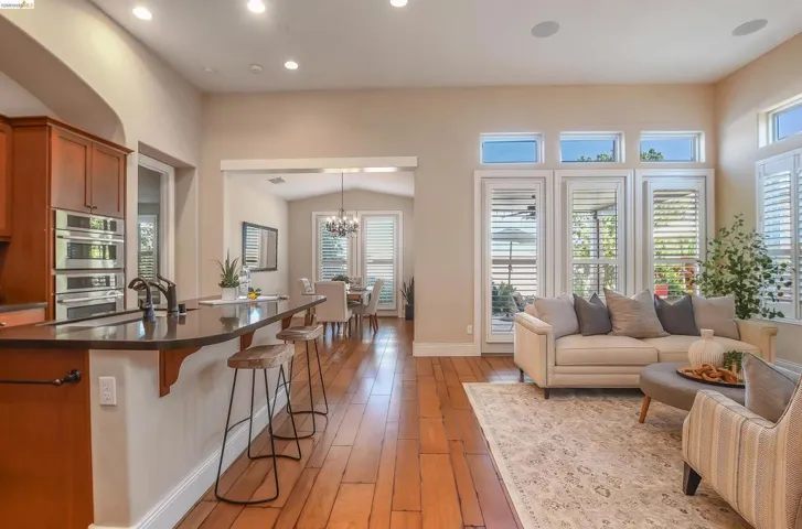 Open-concept living space featuring wood-finish flooring, recessed lighting, and high ceilings