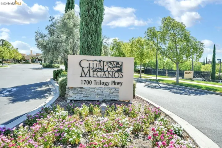 Club Los Meganos entrance sign featuring stacked stone base and metal lettering, surrounded by colorful groundcover plantings