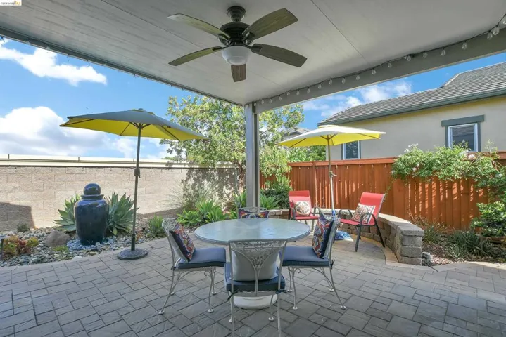 Covered patio featuring a ceiling fan, string lighting, and paver flooring