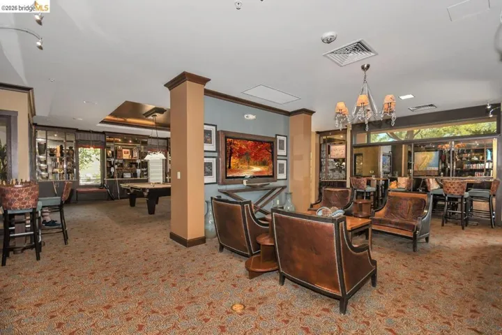 Spacious common area featuring patterned carpeting, recessed lighting, and a crystal chandelier