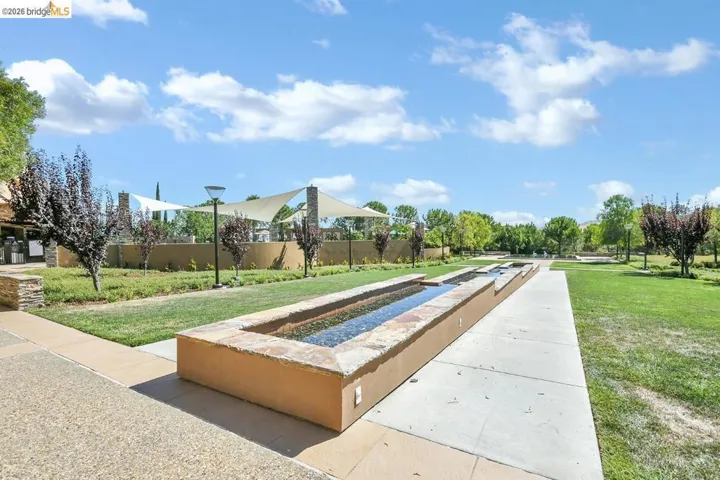 Landscaped outdoor area featuring multiple water features, manicured lawns, and mature trees
