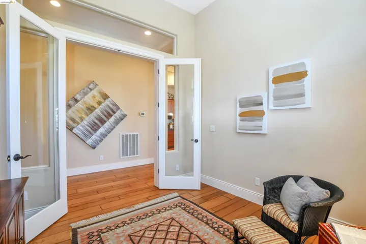 Interior room featuring wood-finish flooring, light-toned wall paint, and a pair of French doors with transom windows